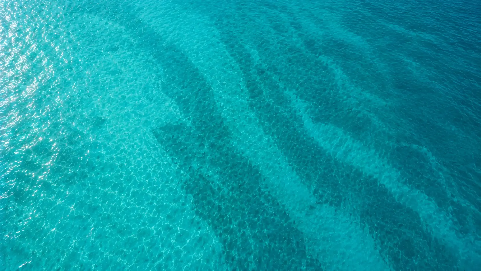 Vista aérea de agua turquesa del Mediterráneo con una moto de agua dibujando una estela circular
