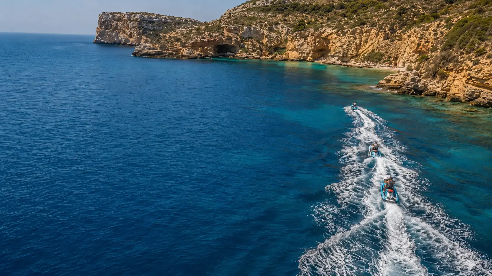 Vista aérea de una moto de agua trazando un círculo sobre aguas turquesa del Mediterráneo